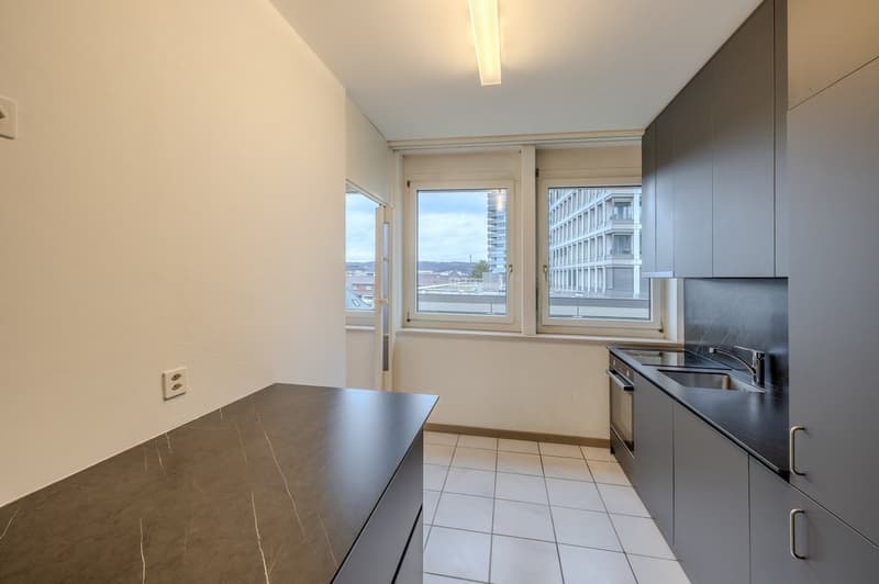 modern kitchen with granite countertops, dark grey cabinets, white tile flooring, double sink, gas stove, large windows