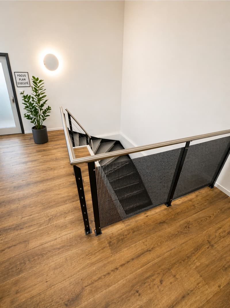 modern staircase with metal railings, wooden floor, black mesh panel, white wall, potted plant