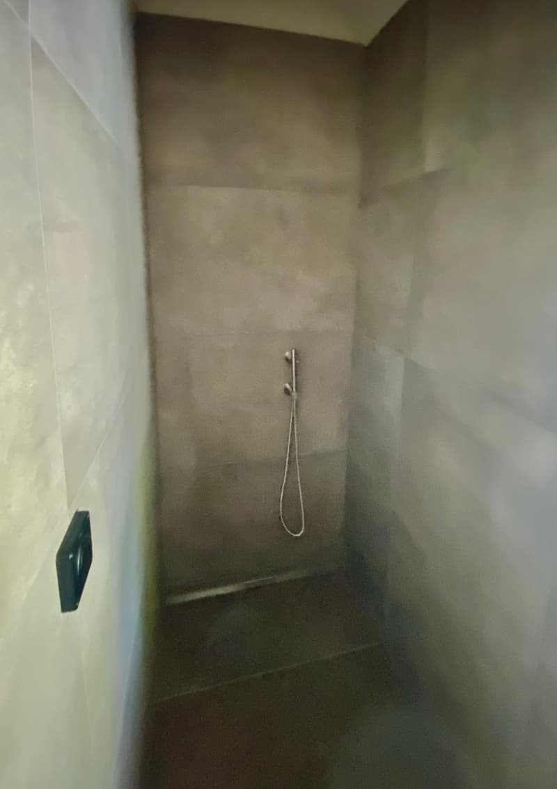 shower with shower head and tiled walls