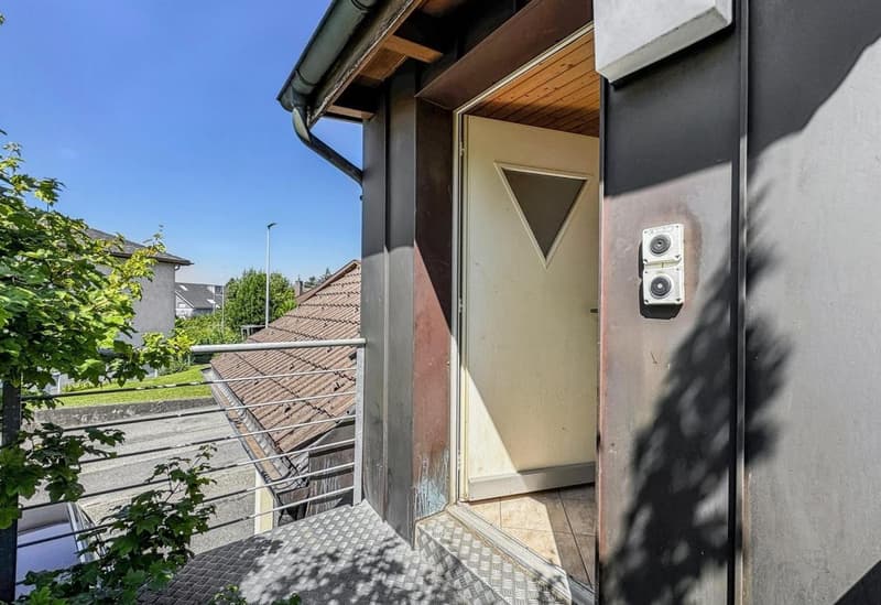 Exterior of a house with a balcony, metal railing, and a door with a triangular window