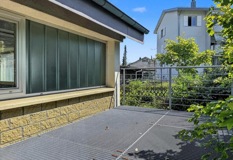 Exterior view of a house with a balcony, brick wall, metal railing, and a window.