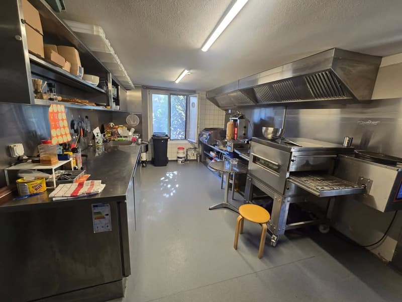 Commercial kitchen with stainless steel appliances, countertops, and a window.