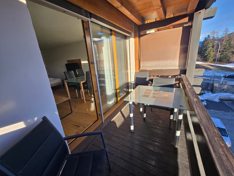 Balcony with wooden floor, glass table, chairs, sliding glass door, wooden ceiling, view of the outside