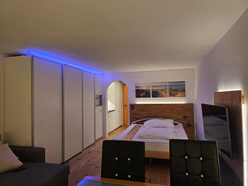 Bedroom with bed, wardrobe, couch, desk, chairs, TV, and pictures on the wall