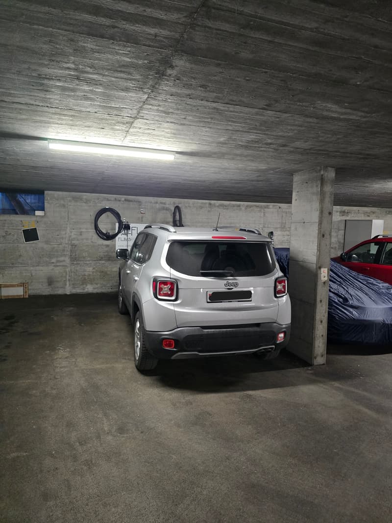underground parking space with concrete walls, silver Jeep parked, red car parked, blue car cover