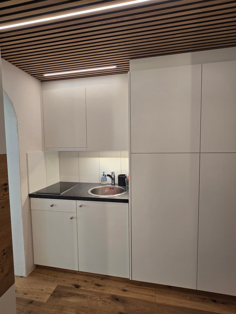 modern kitchen with white cabinets, black countertop, stainless steel sink, wooden floor