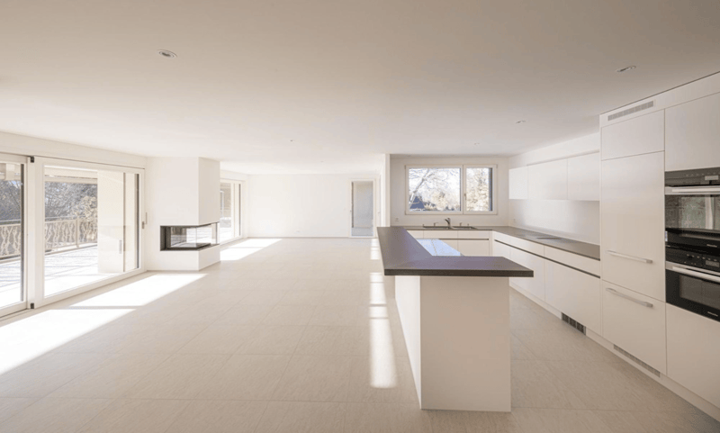 modern kitchen with white cabinets, black countertop, fireplace, large windows, balcony
