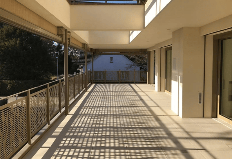 Balcony with tiled floor, metal railings, and a view of a house and trees