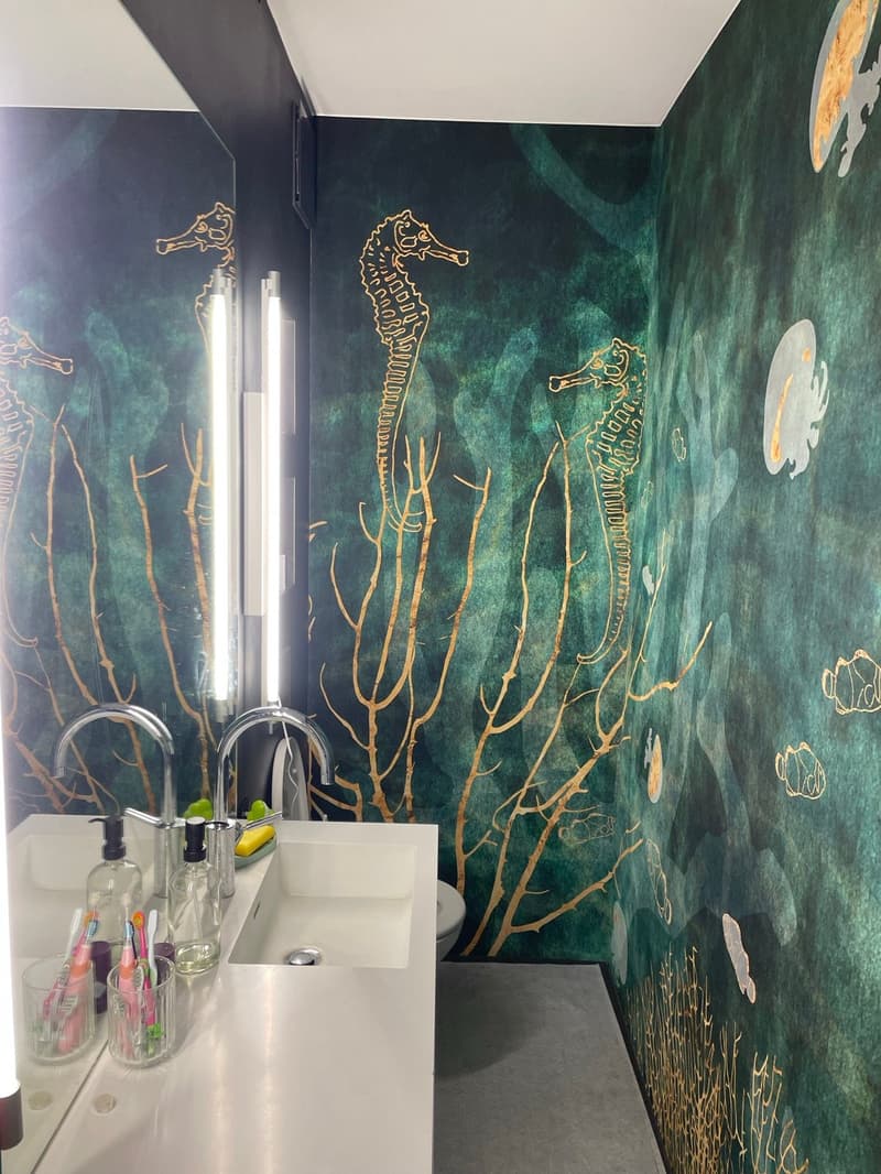 Bathroom with green walls, seahorses and corals wallpaper, double sink, mirror, toilet