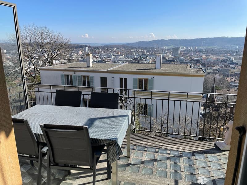 Balcony with table and chairs, metal railing, city view