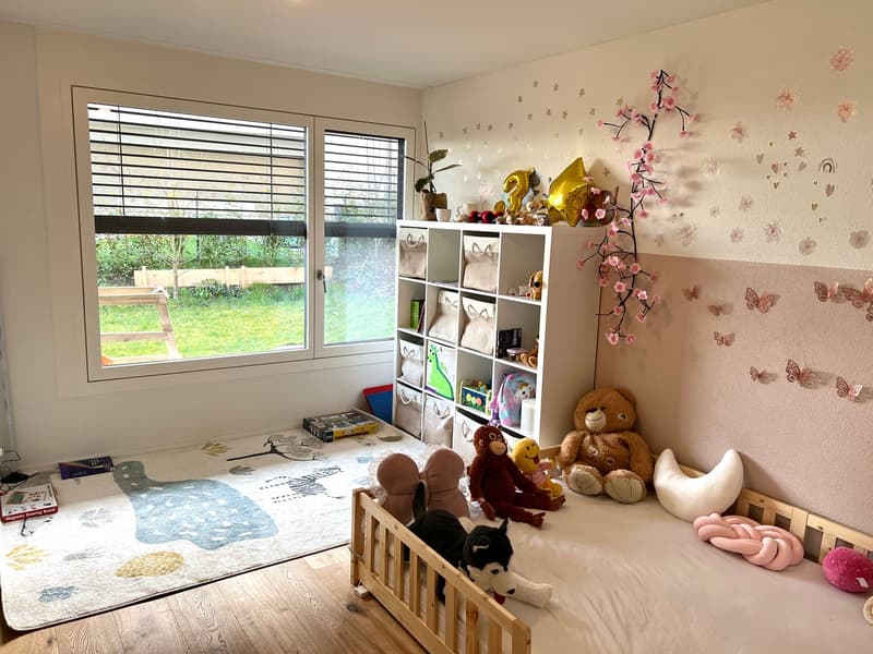 Child's bedroom with wooden crib, toys, rug, shelves, and large window