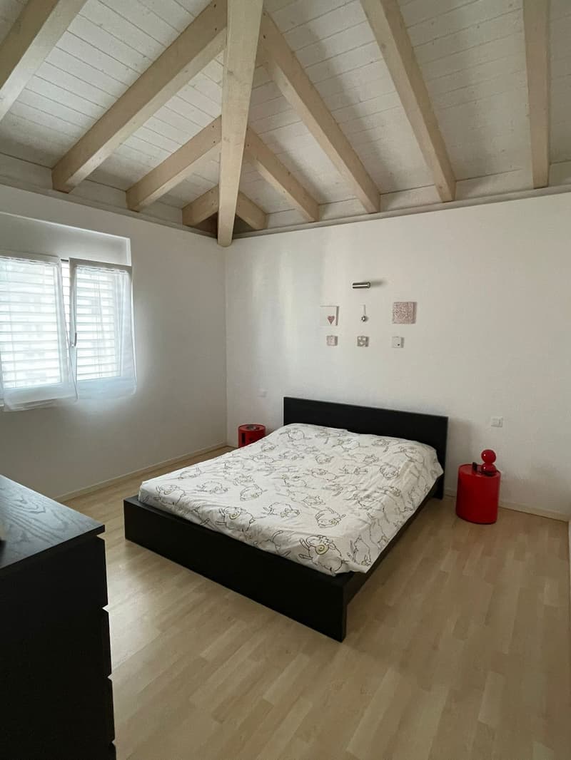 white walls, wooden bed, window with white curtains, wooden floor, bedside tables