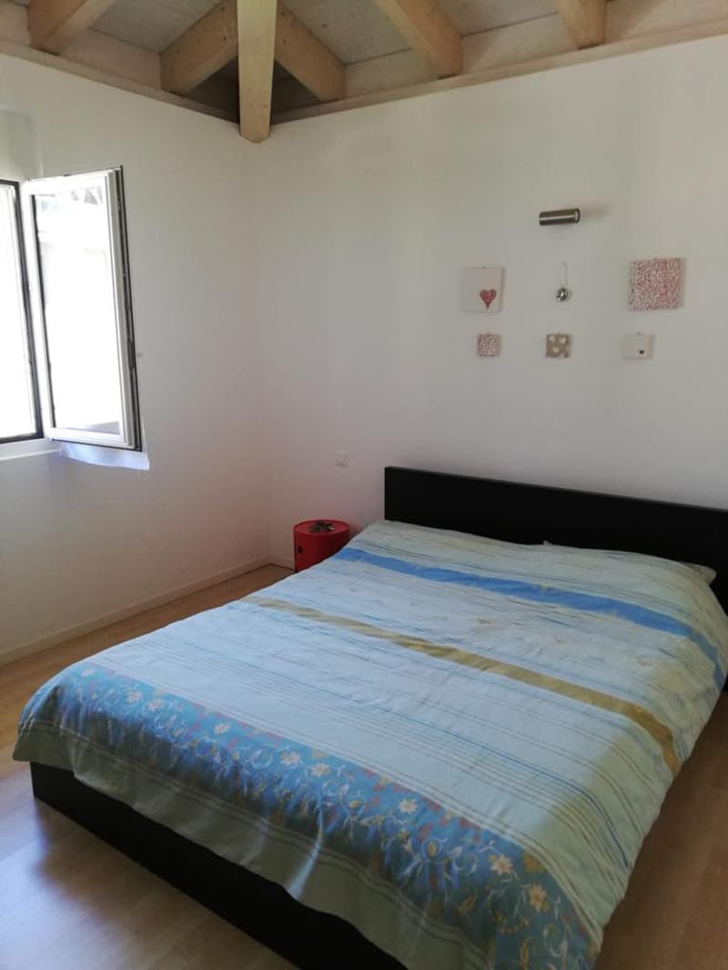 bedroom with a bed, wooden ceiling, white walls, wooden floor, a window with curtains