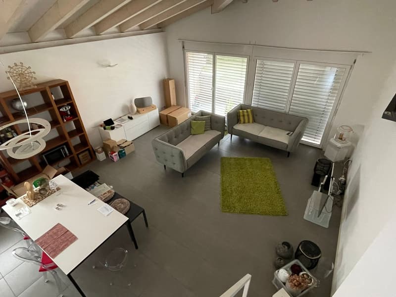 open living area with dining table, grey couches, white table, white and grey walls