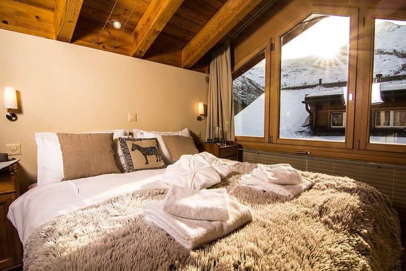 Spacious bedroom with large bed, wooden ceiling, window with view, lamps, desk, towels