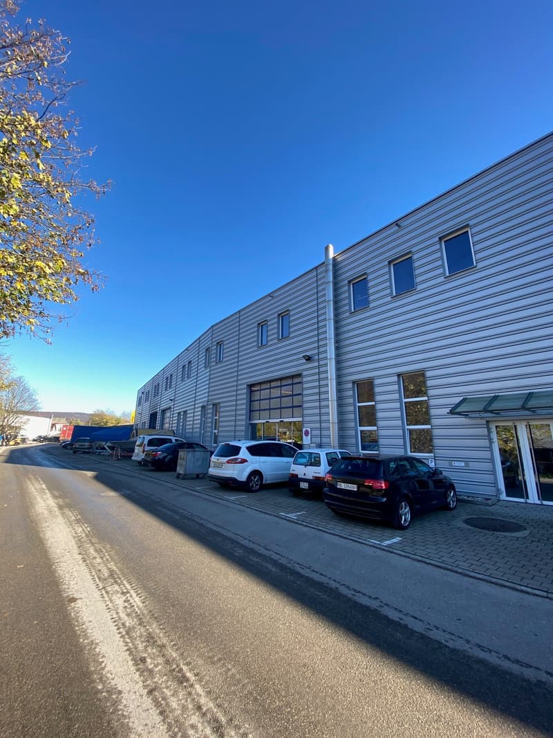 Warehouse with office space, cars parked outside, wide entrance, many windows, modern architecture