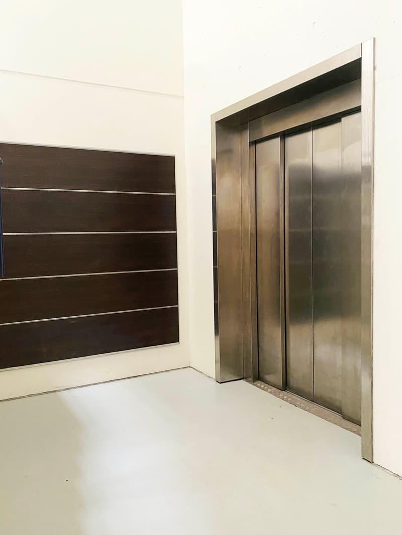 modern elevator, stainless steel panels, open floor plan, wooden wall, polished concrete flooring