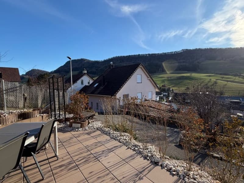 House with a backyard with a dining set, a view of the mountains and houses, paved ground