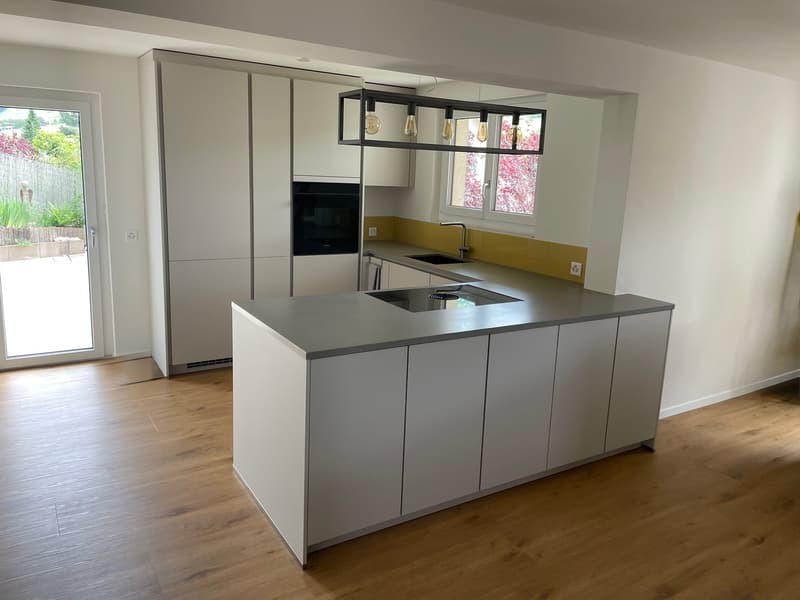 modern open-plan kitchen with island countertop, central island sink, overhead pendant lights, yellow accent wall, white cabinetry, electric oven, dishwasher, kitchen sink, built-in dishwasher