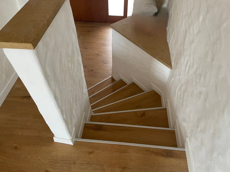 wooden staircase, white walls, hardwood floors, white trims, open space