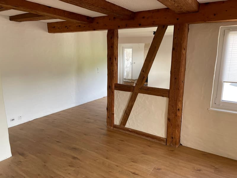 An empty room with wooden beams and white walls, wooden floor.