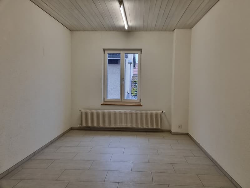 empty room with white walls, tiled floor, white radiator, ceiling light