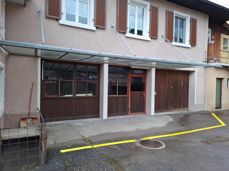 Facade of a house with a garage, glass doors, and a canopy