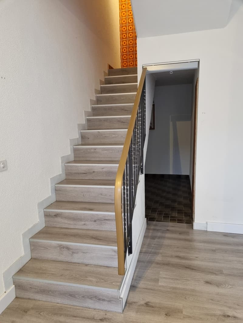 wooden staircase with white walls and grey tiles