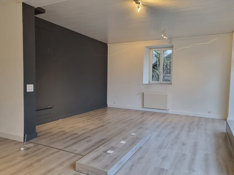Empty room, hardwood floor, white walls, single window, wall-mounted radiator, power outlets