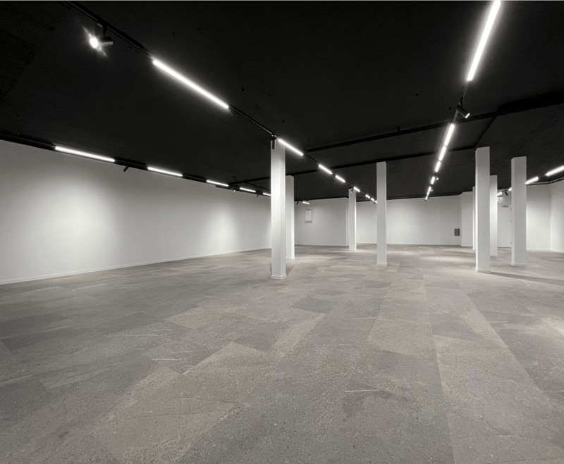 empty room with gray tiles, tall white columns, white walls, bright ceiling lights