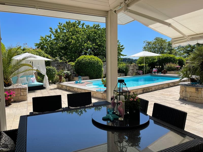 outdoor dining area with a glass table and a swimming pool