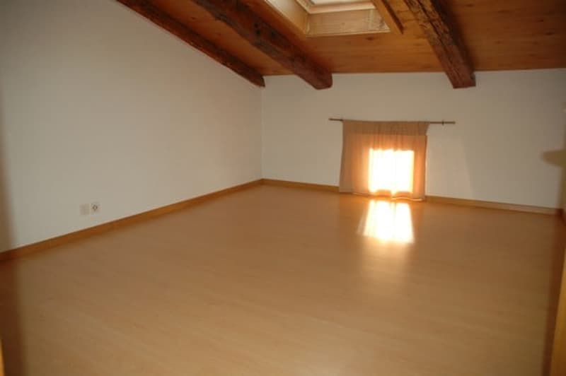 Empty room with wood flooring, white walls, wooden ceiling, a window with a curtain.