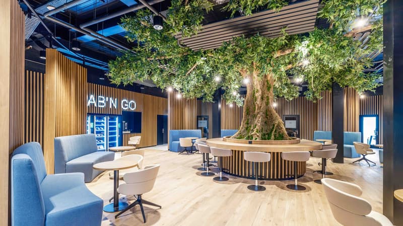 large tree center, blue couches, small tables, modern design, blue lighting