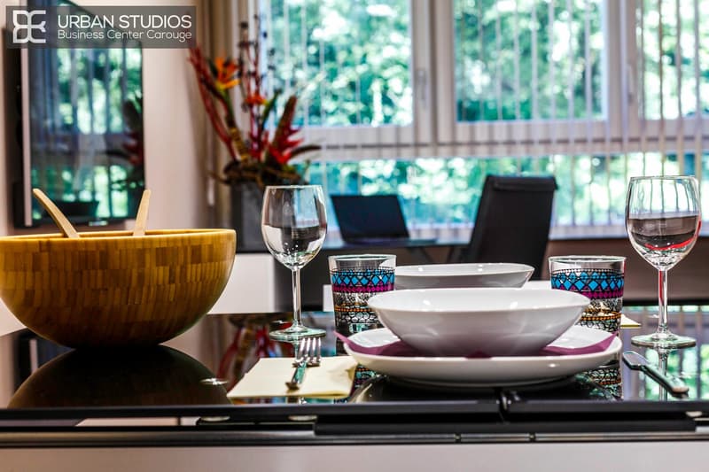 Dinner set on a glass table with large bowl, plates, cups, wine glasses, chopsticks, knife and fork