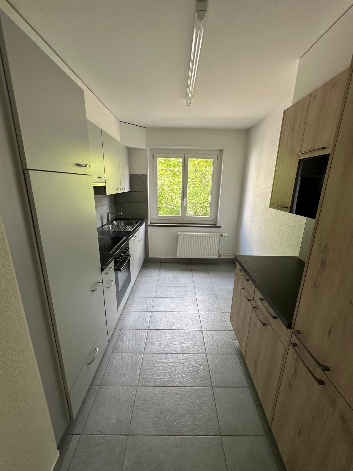 modern kitchen with white cabinets, black countertops, tiled floor, window with view