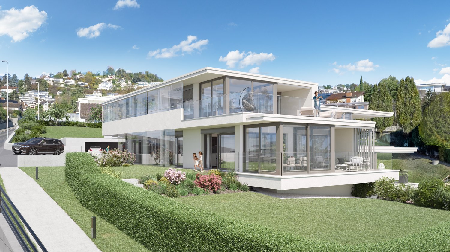 Two-story modern house with large glass windows, balcony, garage, and parking space. The house is surrounded by a well-manicured lawn and landscaping with flowers and shrubs.