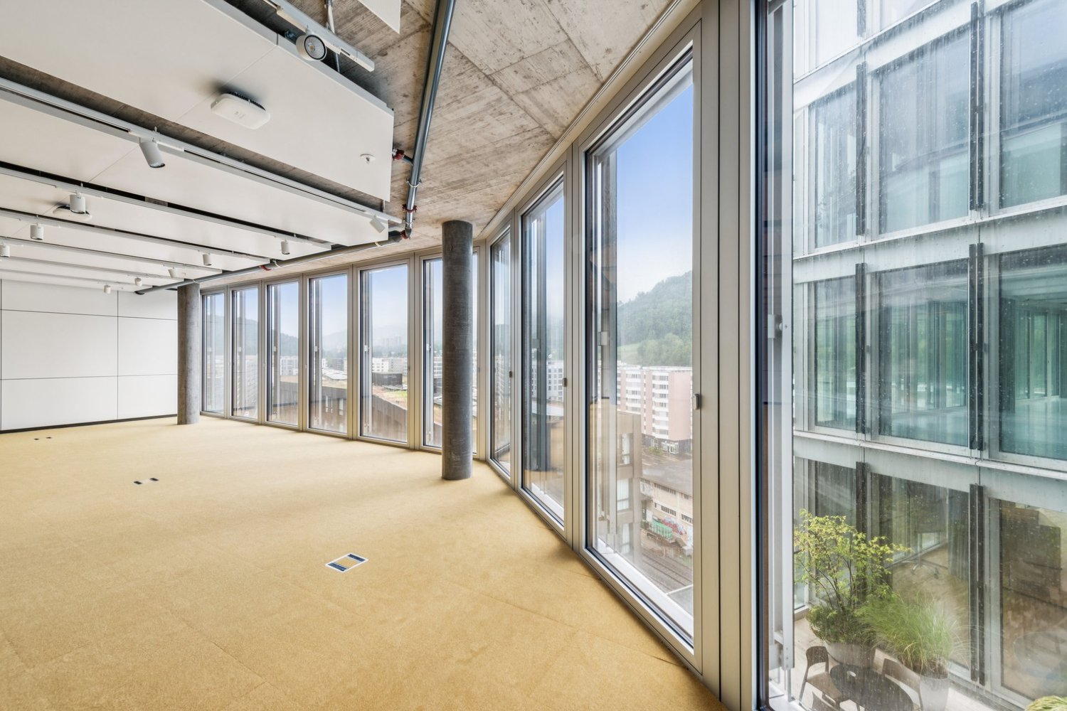 Wide windows with city view, carpeted floor, central column