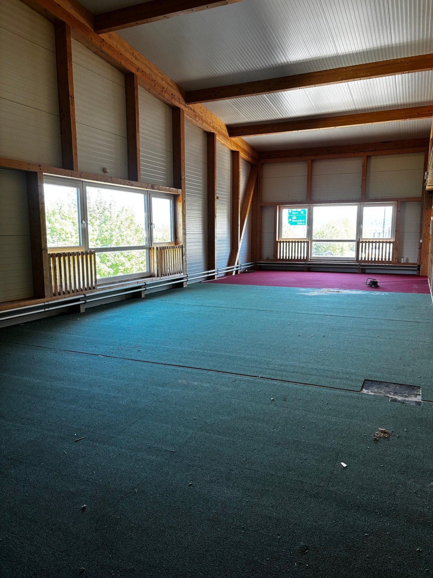 large room, wooden beams, large windows, green carpet, red carpet