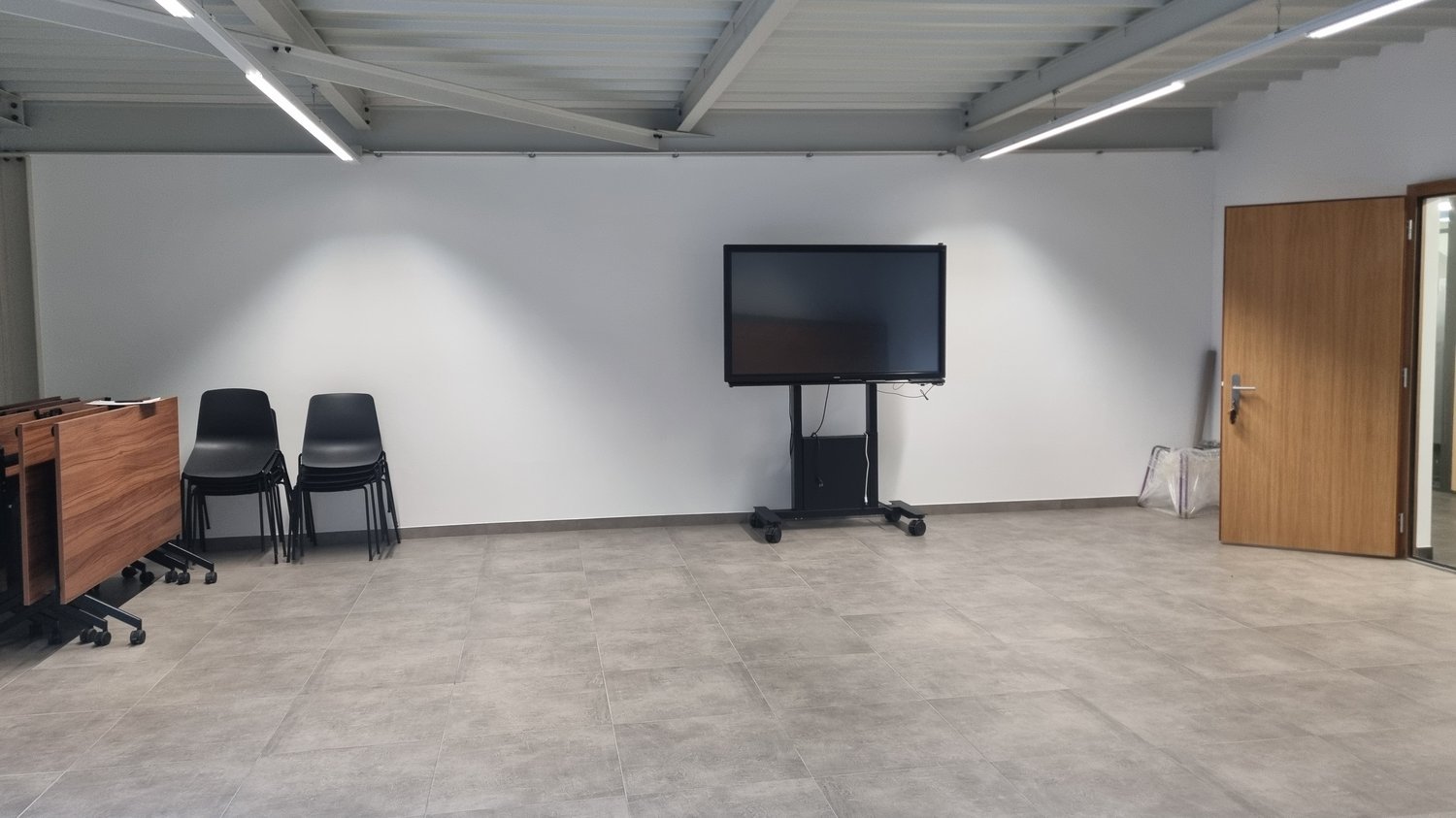room with tiled floor, two chairs, mounted monitor, wooden door