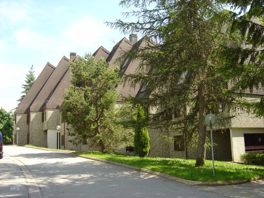 Row of houses with brown roofs, stone walls, windows, and garages