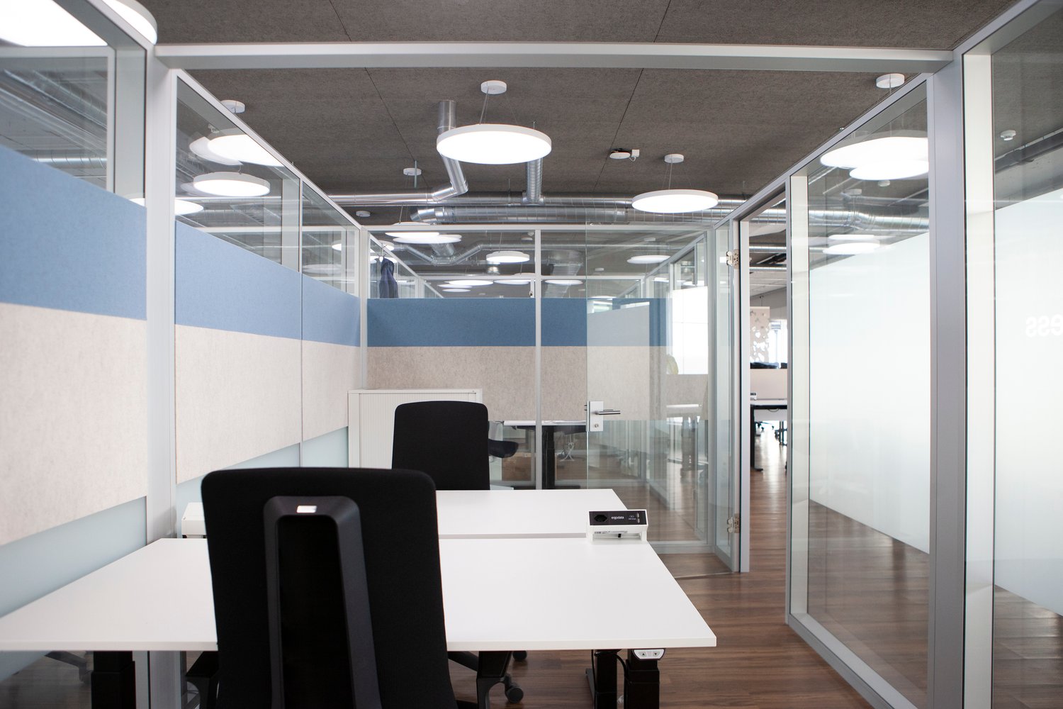 glass walls, white desk, black office chairs, ceiling lamps