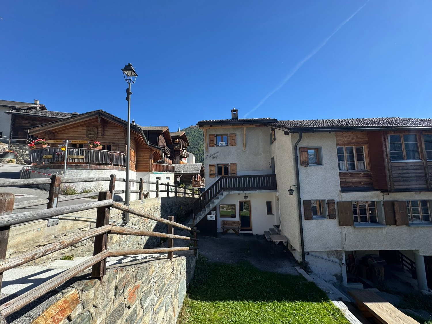 Swiss chalet style house, large wooden balcony, raised ground floor, wooden fencing, garden