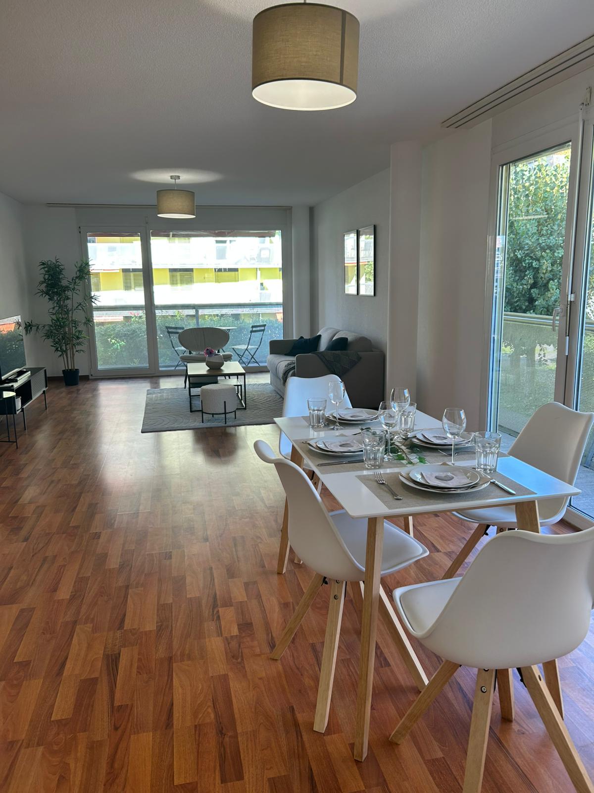 modern dining room with white chairs, wooden floor, dining table, open balcony, glass door