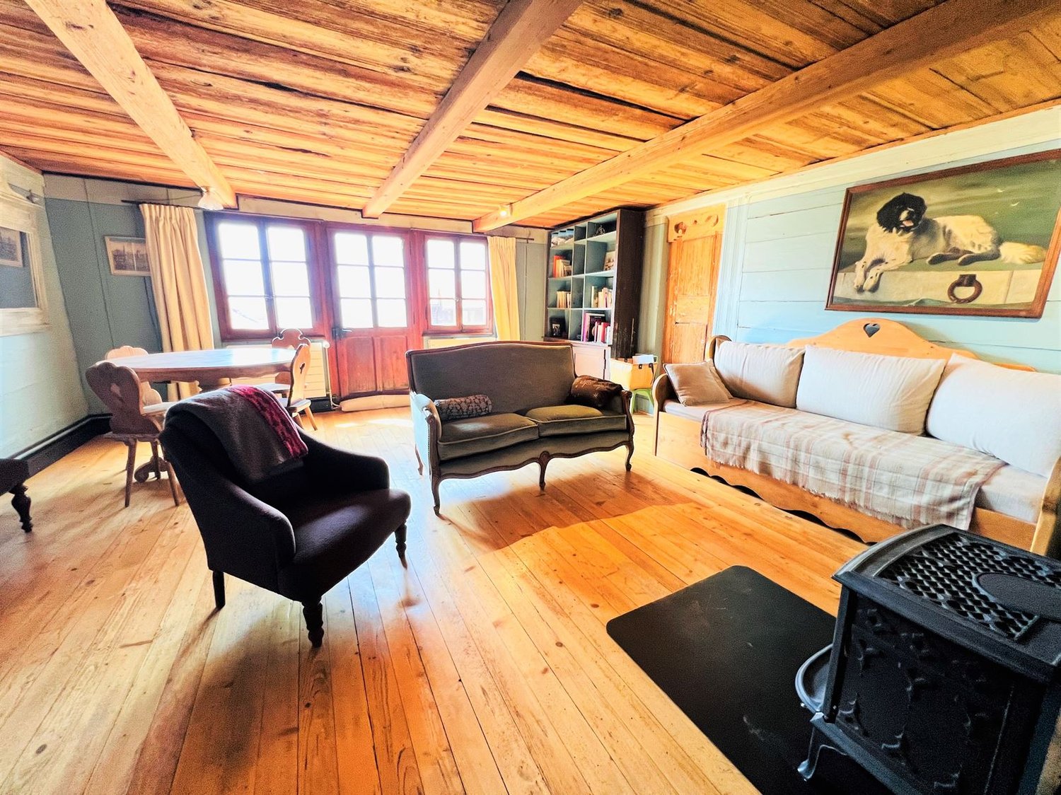 wooden floor, wooden beams, fireplace, sofa, couch, chair, table, bookshelf, painting