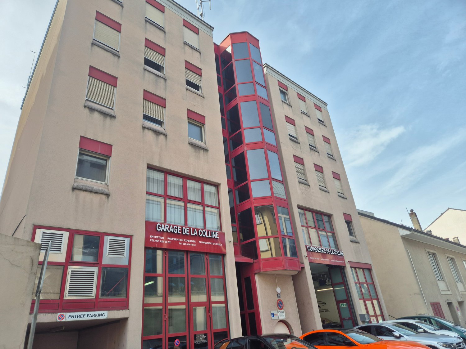 Multi-story building, red trim, large windows, underground garage