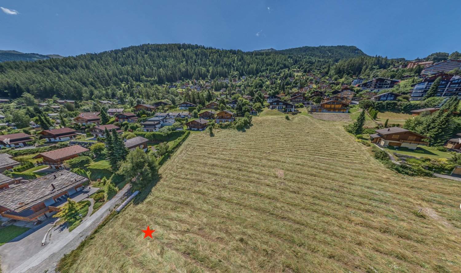 Plot of land for development in a mountainous area with several chalets, surrounded by forests and mountains