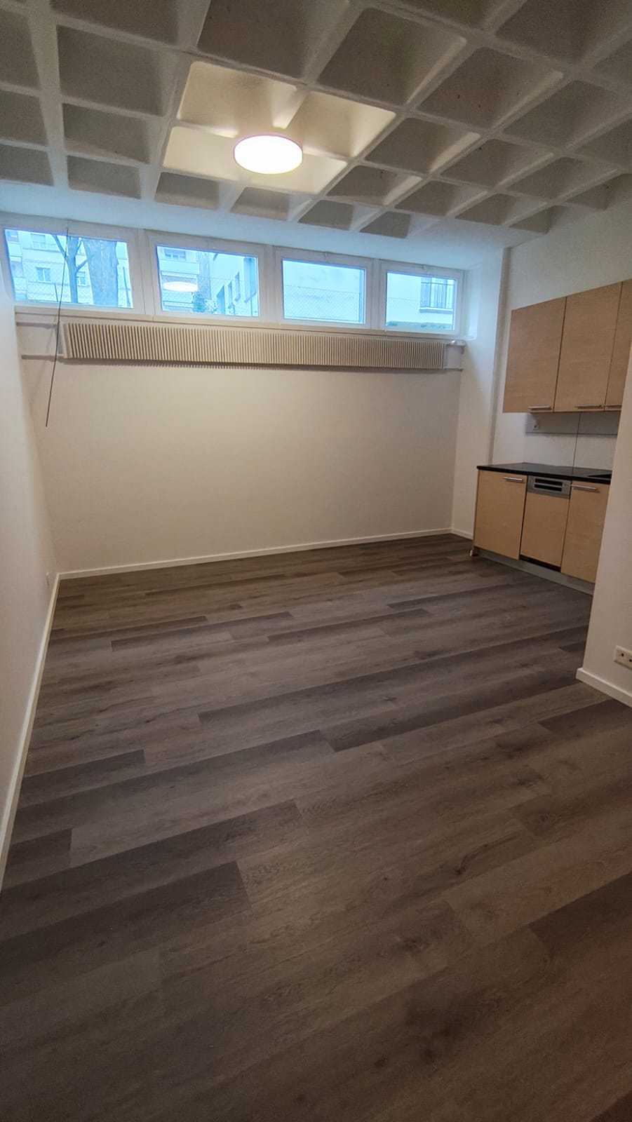 empty room, wooden floor, white walls, kitchen area with cabinets and dishwasher