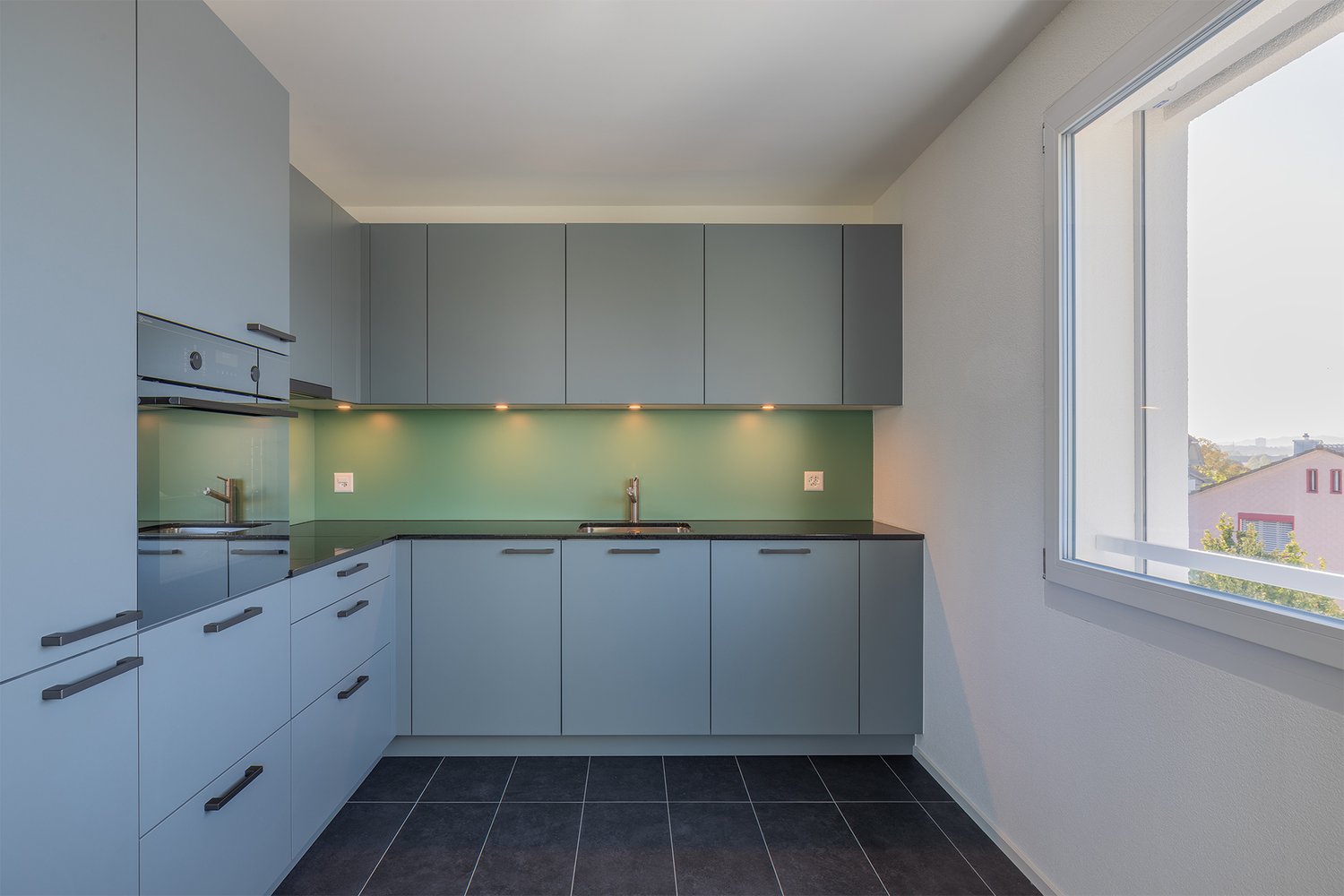 Modern kitchen, gray cabinets, black countertops, stainless steel faucet, large window