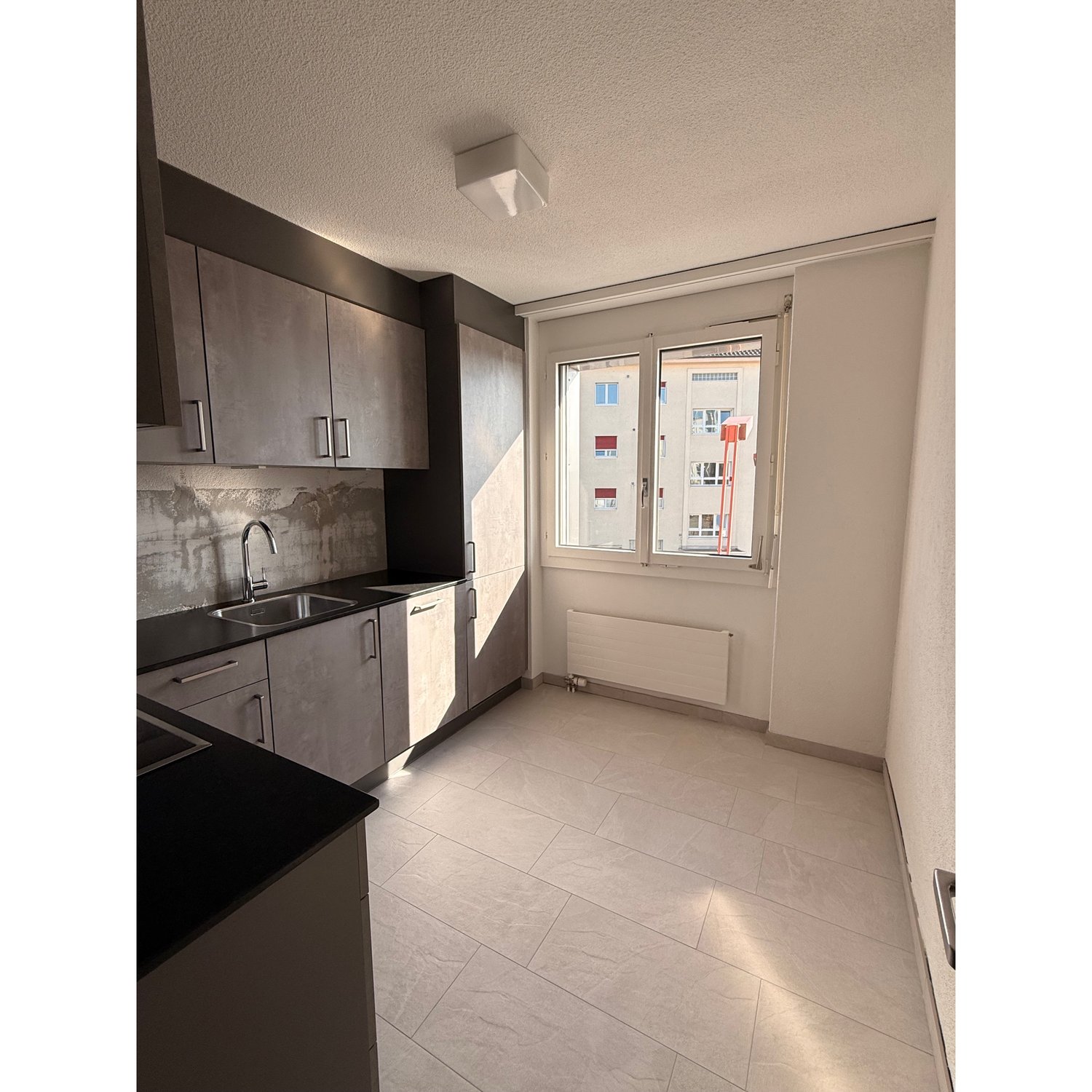 modern kitchen, white tiles, black countertops, stainless steel sink, cabinets, window
