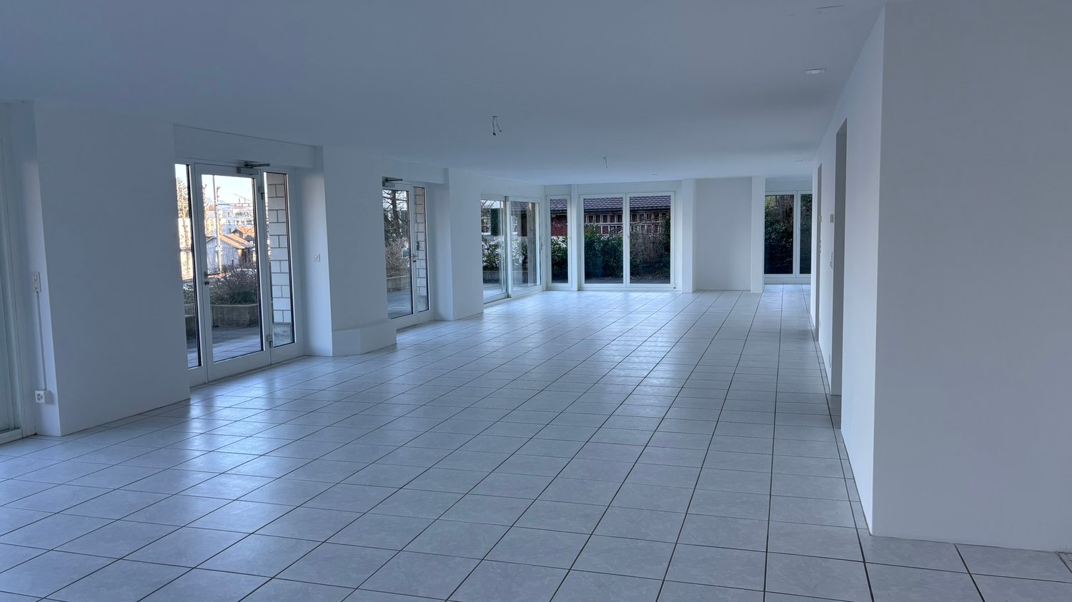 empty room, white walls, glass doors, glass windows, tiled floor, view of outside